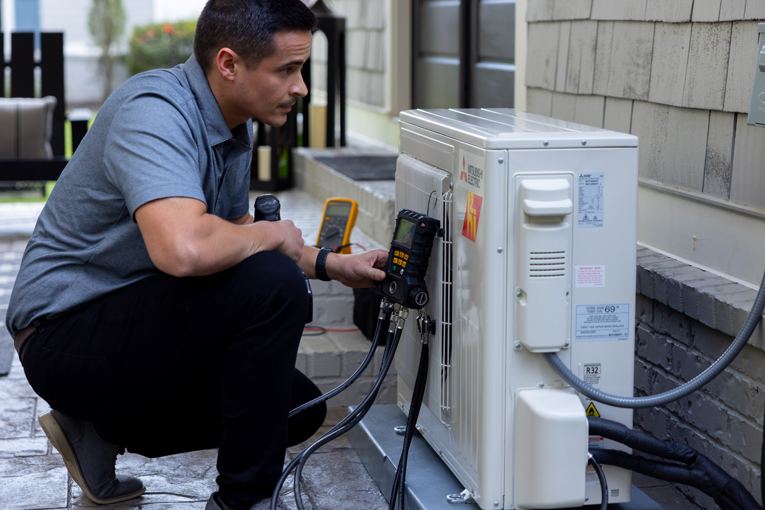 Technician servicing HVAC unit with pressure gauge and tools in residential setting, highlighting PROTECH HVAC LLC's expertise in heating and cooling solutions for Ocean City, MD.
