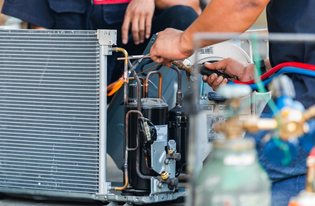 Technician repairing HVAC system with tools and refrigerant lines, highlighting expert service from PROTECH HVAC LLC in Ocean City, MD.