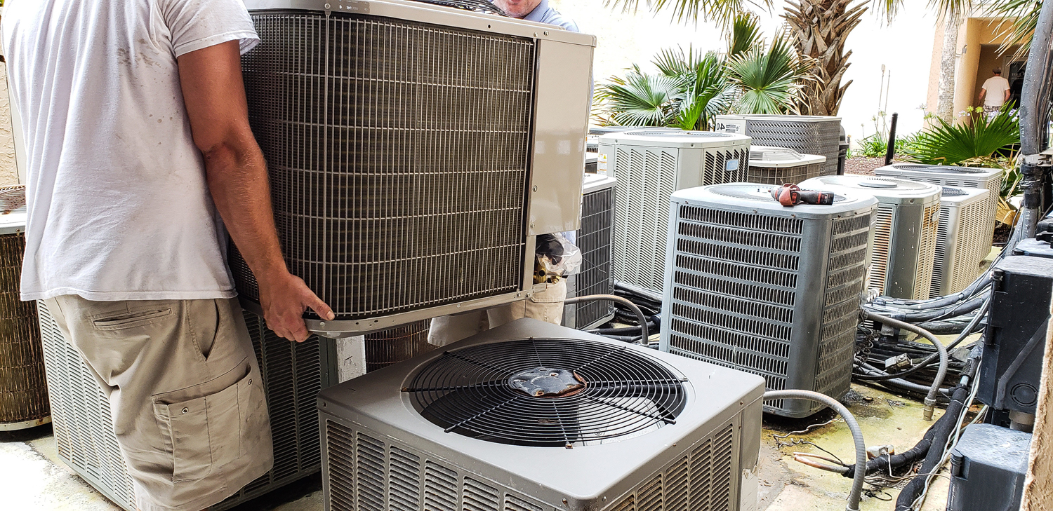 Technician installing a heat pump unit among multiple HVAC systems, emphasizing dual fuel system installation for efficient heating and cooling.